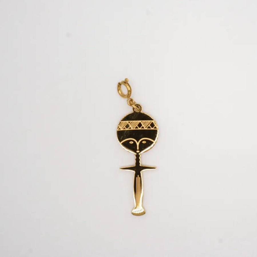 Gold pendant with a black design on a white background. fertility, motherhood symbol
